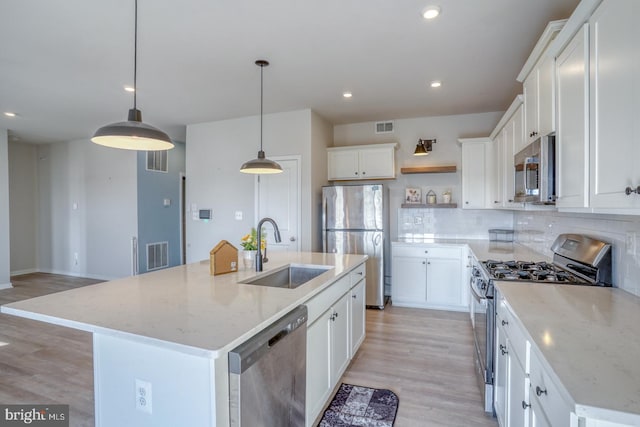 kitchen featuring decorative backsplash, visible vents, appliances with stainless steel finishes, and a sink