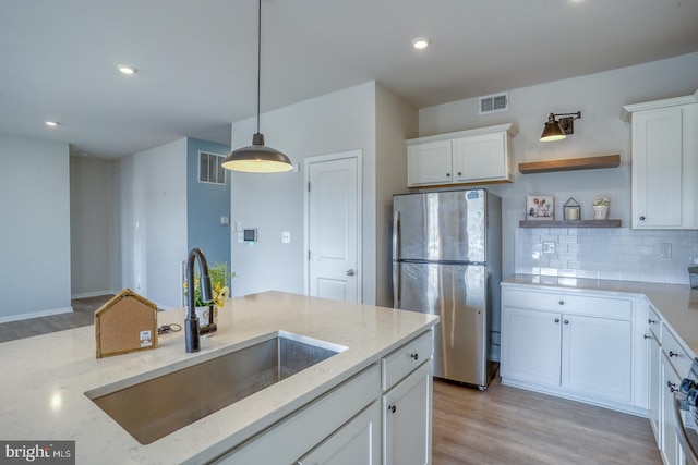 kitchen featuring open shelves, visible vents, freestanding refrigerator, and a sink