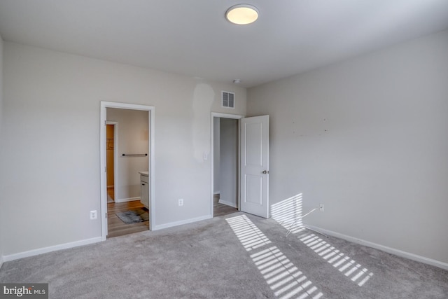 unfurnished bedroom with baseboards, visible vents, carpet floors, and connected bathroom