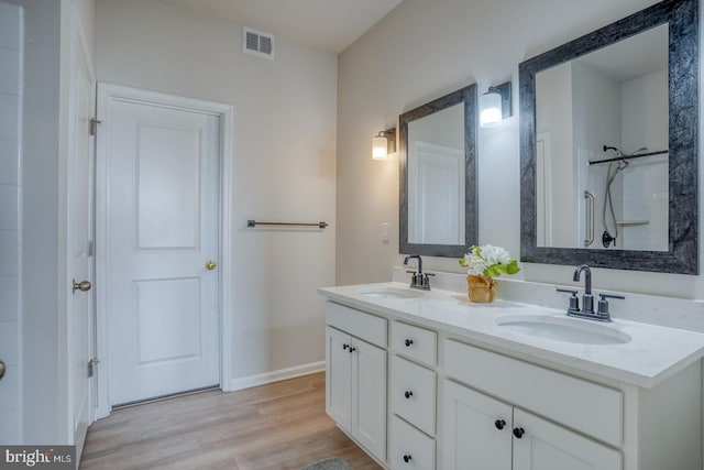 bathroom featuring double vanity, visible vents, wood finished floors, and a sink