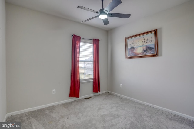 carpeted empty room with a ceiling fan, visible vents, and baseboards