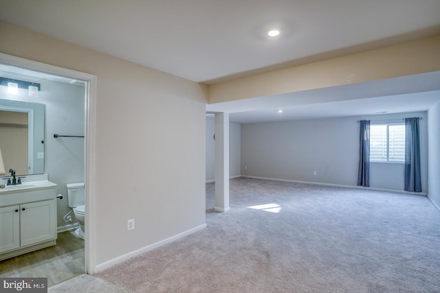 interior space with a sink, baseboards, and light colored carpet