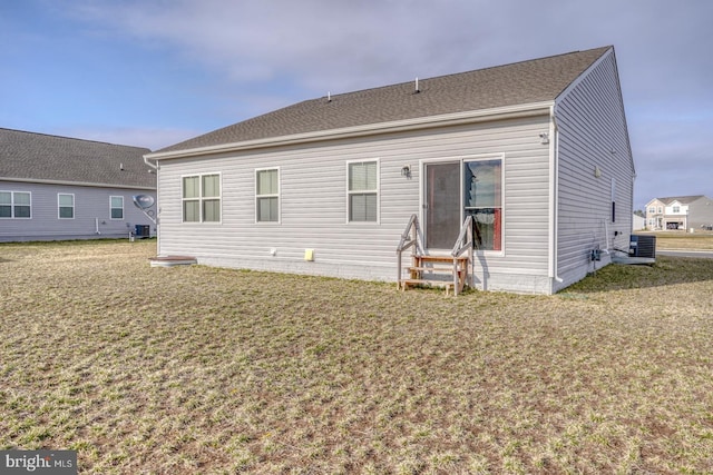 rear view of house featuring entry steps, central air condition unit, and a yard