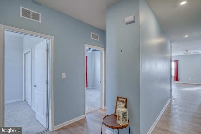 hallway featuring recessed lighting, visible vents, baseboards, and wood finished floors