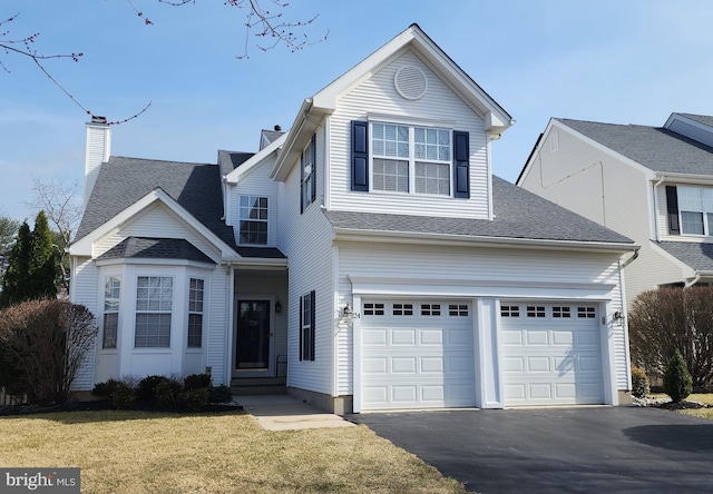 traditional-style house featuring aphalt driveway, a garage, and a front yard