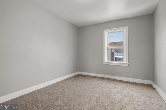 carpeted empty room featuring baseboards