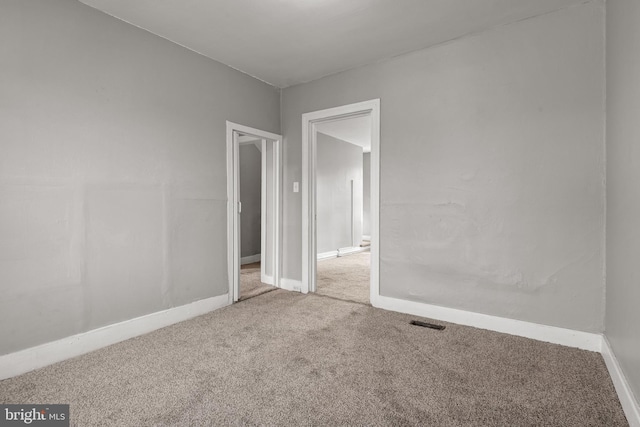 carpeted empty room featuring visible vents and baseboards