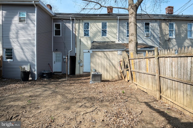 back of house with a chimney, central AC, and fence