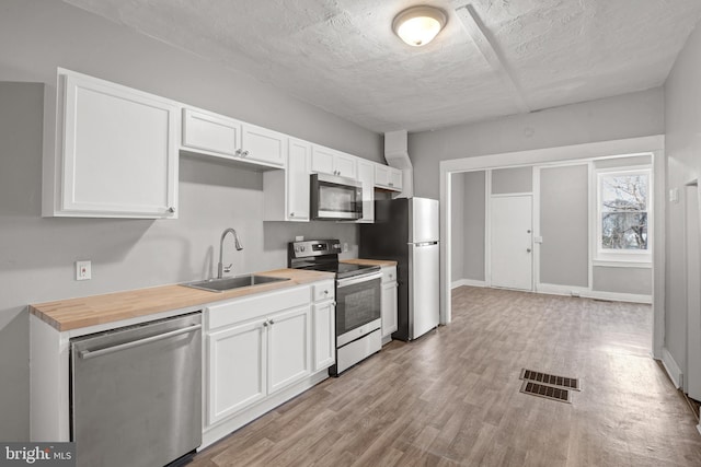 kitchen with a sink, white cabinets, visible vents, and stainless steel appliances