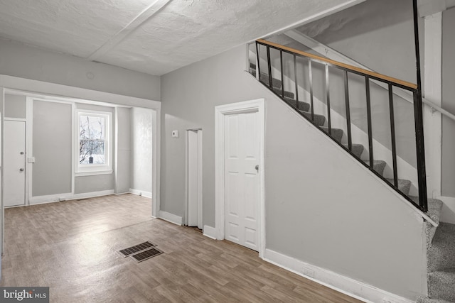 foyer with visible vents, baseboards, wood finished floors, and stairs