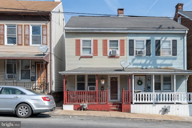 townhome / multi-family property featuring a shingled roof, covered porch, and a chimney