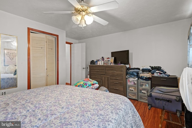 bedroom with a closet, a textured ceiling, a ceiling fan, and wood finished floors