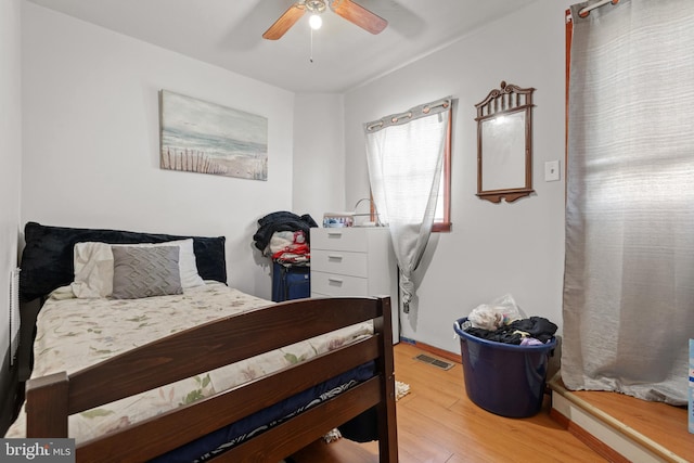 bedroom with a ceiling fan, wood finished floors, and visible vents