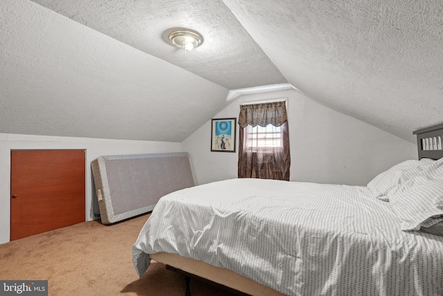 bedroom with vaulted ceiling, a textured ceiling, and carpet floors