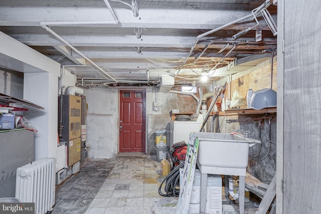 unfinished basement featuring a sink, washer / clothes dryer, and radiator heating unit