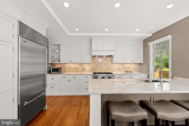 3517 Woodbine St, Chevy Chase, MD 20815 - kitchen featuring a sink, white cabinetry, appliances with stainless steel finishes, and a kitchen breakfast bar