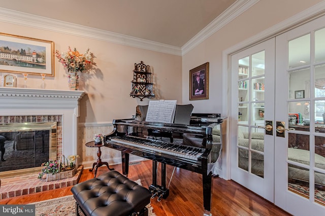 sitting room featuring french doors, wood finished floors, a fireplace, and ornamental molding