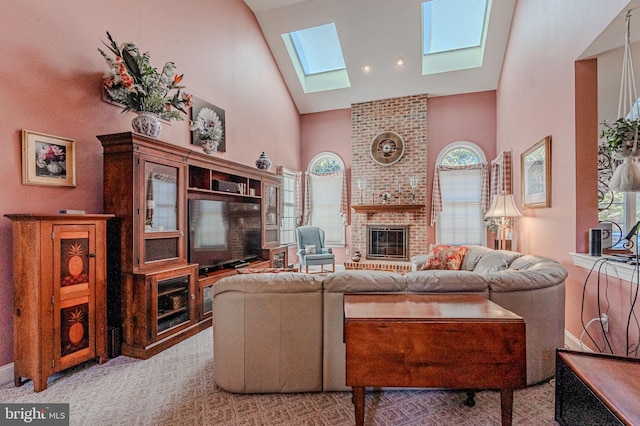 living room featuring high vaulted ceiling, light colored carpet, a brick fireplace, and a skylight