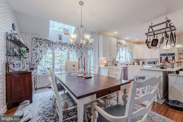 dining space featuring baseboards, wallpapered walls, light wood-style flooring, recessed lighting, and a notable chandelier