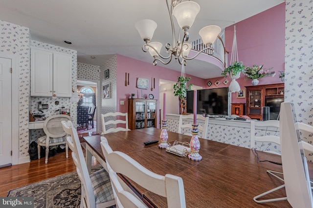 dining room with a chandelier, wallpapered walls, and wood finished floors