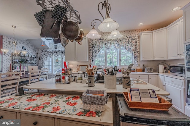 kitchen with wallpapered walls, stainless steel microwave, light countertops, and white cabinetry