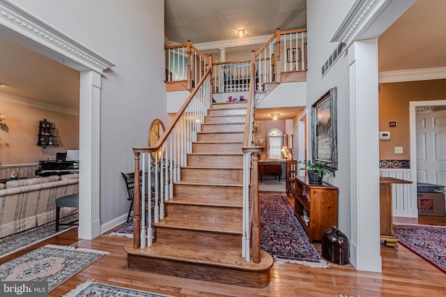 stairs featuring crown molding, a towering ceiling, and hardwood / wood-style flooring