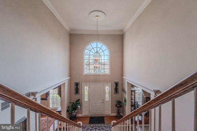 foyer featuring stairs, crown molding, baseboards, and a towering ceiling