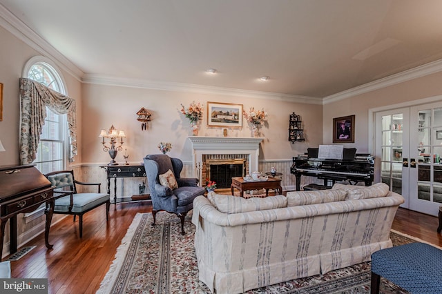 living room with a brick fireplace, ornamental molding, wainscoting, and hardwood / wood-style flooring