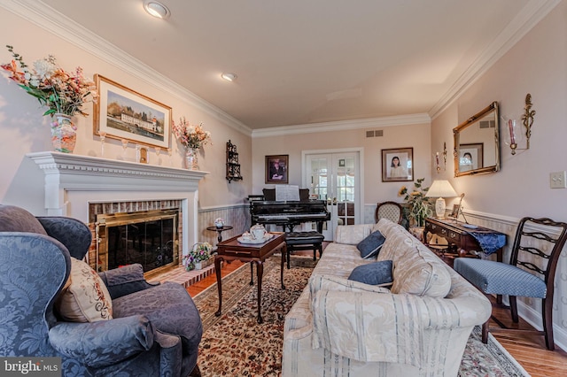 living room with wood finished floors, visible vents, french doors, wainscoting, and crown molding