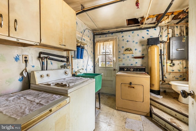 kitchen with a sink, electric panel, washing machine and dryer, and stone tile flooring