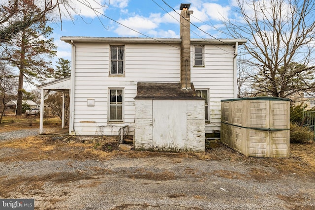 back of house with an outbuilding and a chimney