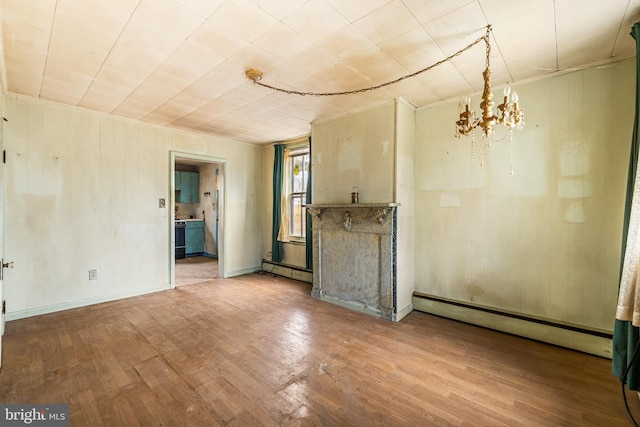 unfurnished living room with baseboard heating, an inviting chandelier, and wood finished floors