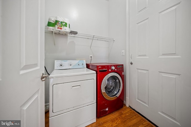 laundry room featuring washing machine and clothes dryer, wood finished floors, and laundry area