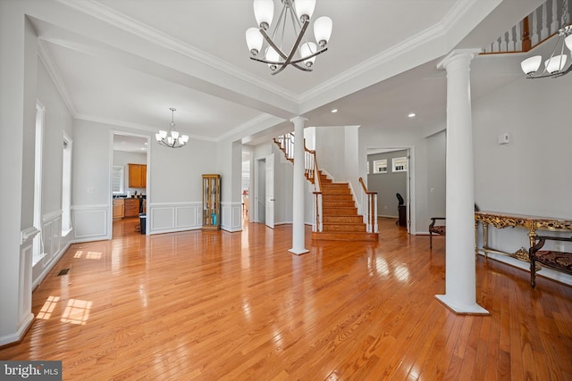 unfurnished living room with recessed lighting, light wood finished floors, an inviting chandelier, crown molding, and decorative columns