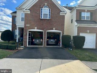 view of front facade featuring driveway, brick siding, and a garage