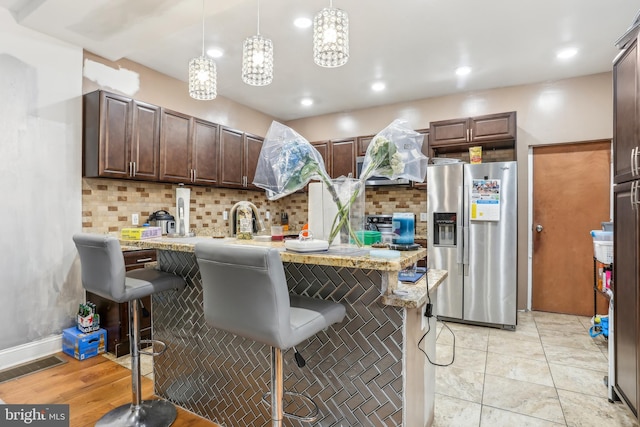 kitchen featuring a kitchen breakfast bar, tasteful backsplash, visible vents, and stainless steel fridge