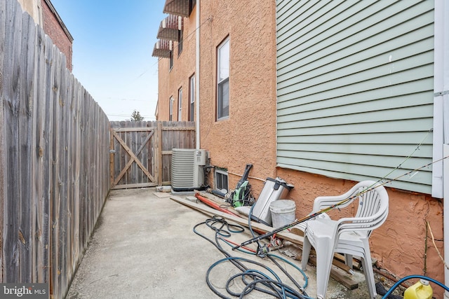 view of patio with a gate, central AC unit, and fence