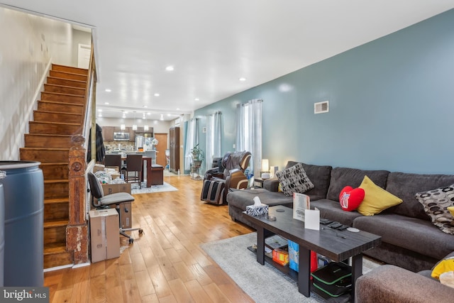 living room with recessed lighting, visible vents, light wood-style flooring, and stairs