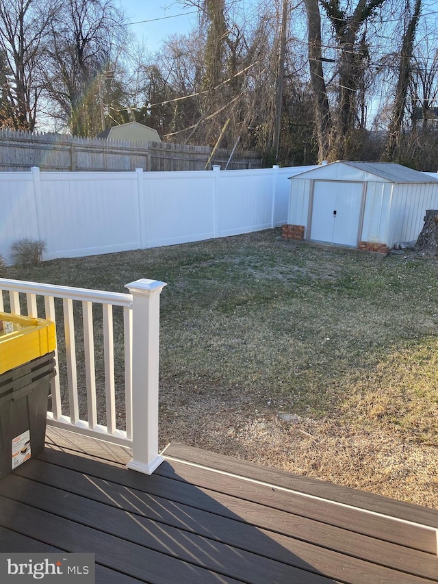 view of yard with an outbuilding, a shed, a fenced backyard, and a deck