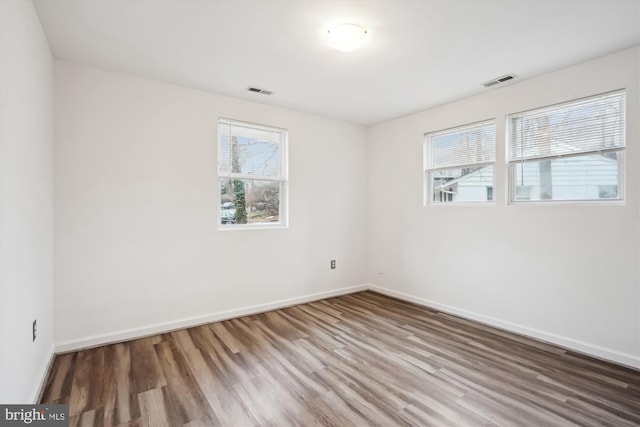 unfurnished room featuring visible vents, baseboards, and wood finished floors