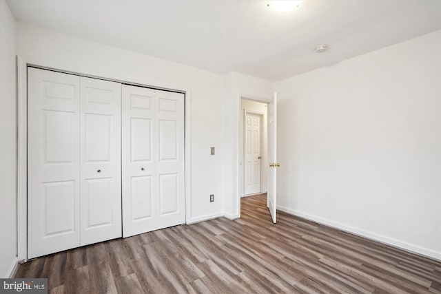 unfurnished bedroom with wood finished floors, a closet, and baseboards