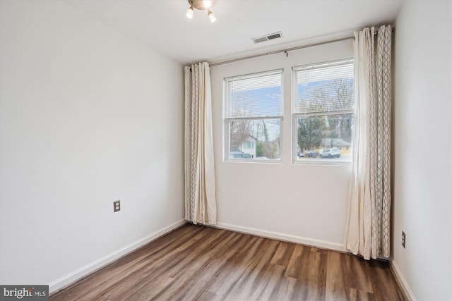 spare room with visible vents, baseboards, and wood finished floors