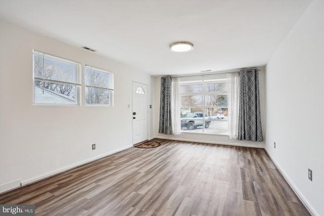 foyer with wood finished floors, visible vents, and baseboards