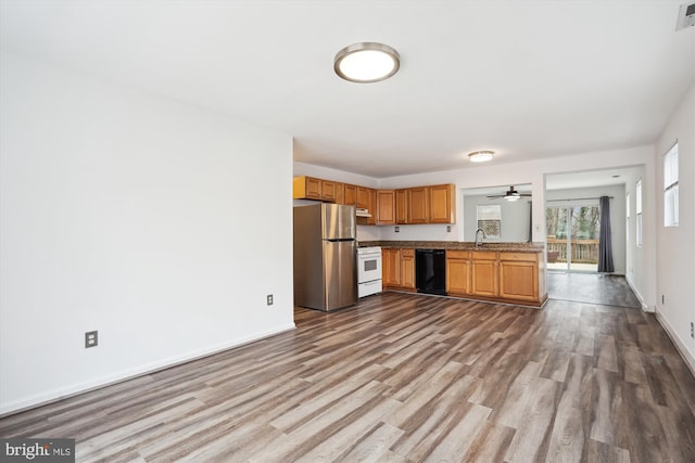 kitchen with dark wood-type flooring, a sink, gas range gas stove, black dishwasher, and freestanding refrigerator