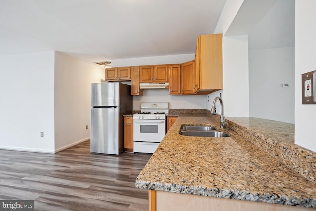 kitchen with visible vents, a sink, under cabinet range hood, white gas range oven, and freestanding refrigerator