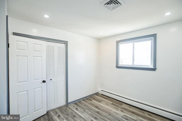 unfurnished bedroom with visible vents, recessed lighting, light wood-style floors, a closet, and a baseboard radiator