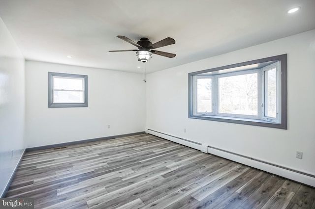 empty room with wood finished floors, recessed lighting, a baseboard radiator, baseboards, and ceiling fan