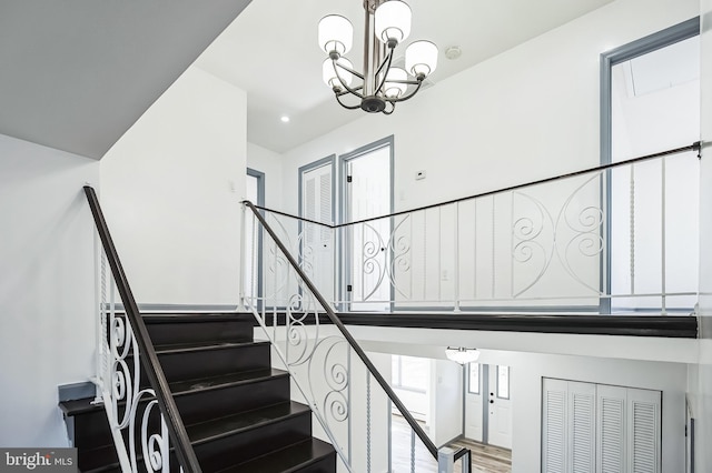 staircase with an inviting chandelier and wood finished floors