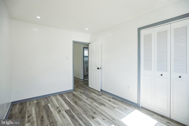 unfurnished bedroom featuring a closet, recessed lighting, light wood finished floors, and baseboards