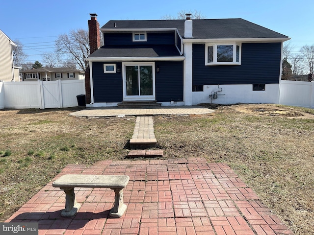 rear view of house featuring a gate, a yard, a fenced backyard, a chimney, and entry steps